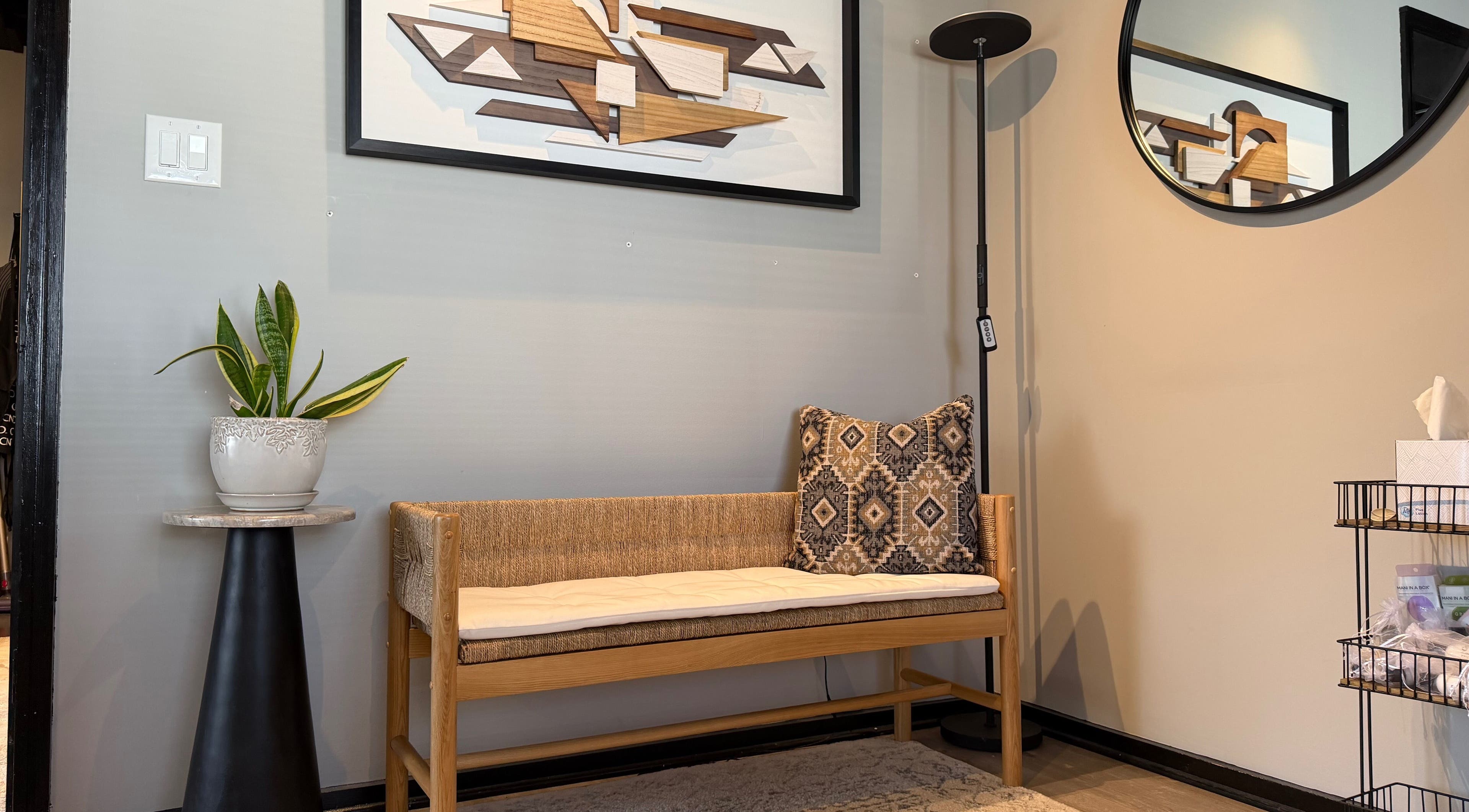 Stylish waiting area at Polished in Valparaiso, Indiana, US with art, cozy bench, and plant decor.