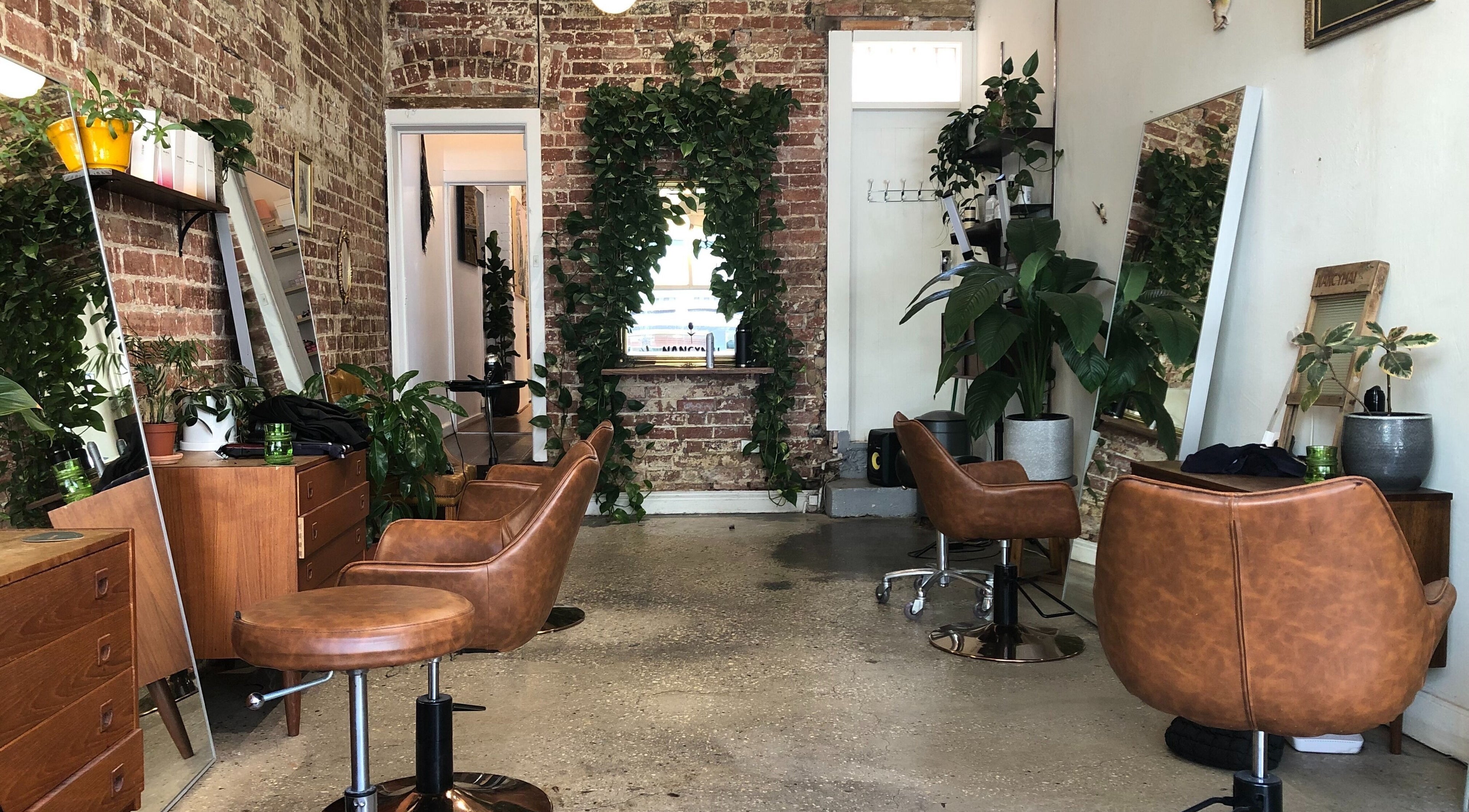 Cozy salon interior with vintage chairs and greenery at Nancymai, Prahran, Victoria, AU.