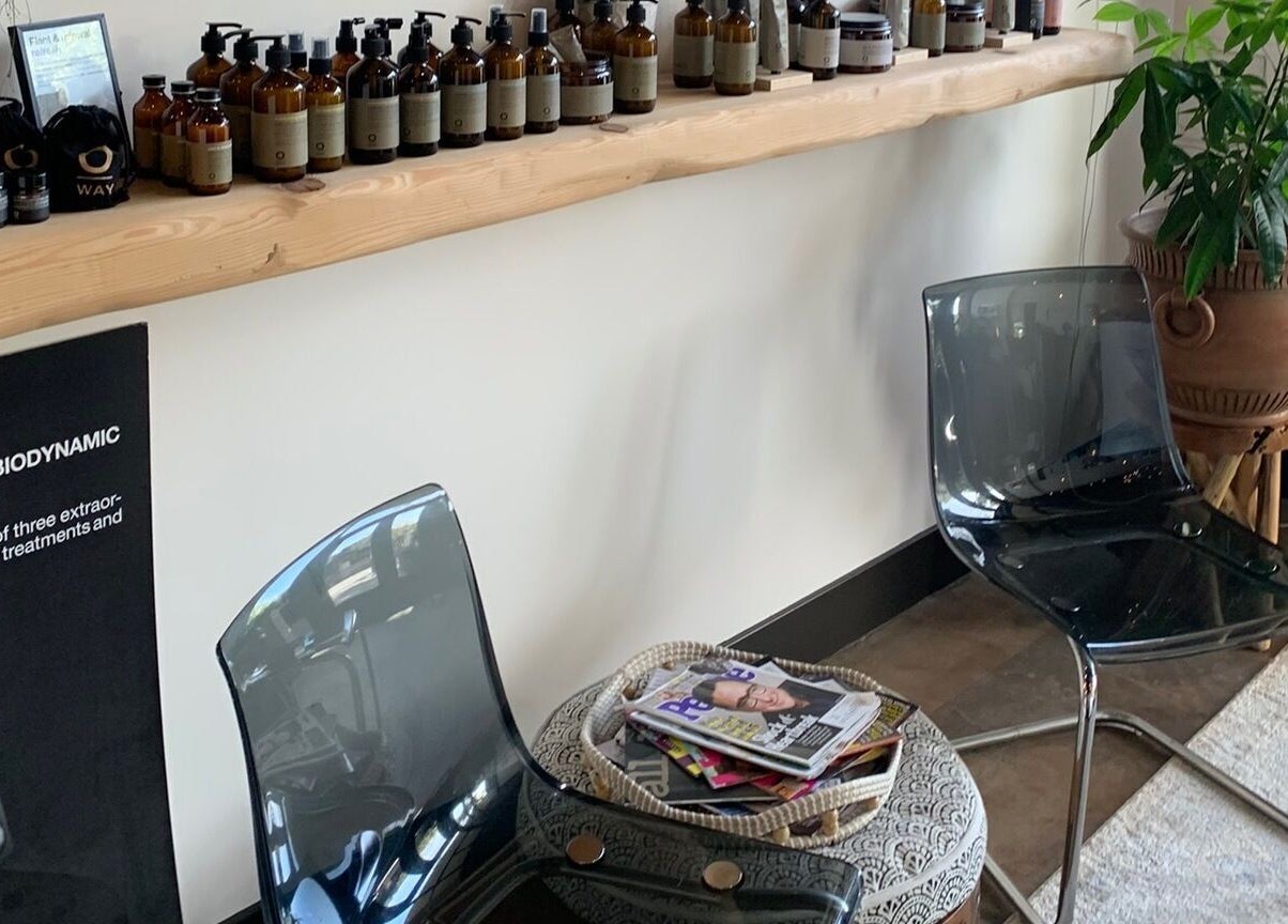Relaxing seating area at Adriana at Salon Vivo, San Carlos, California, US, with products and greenery.