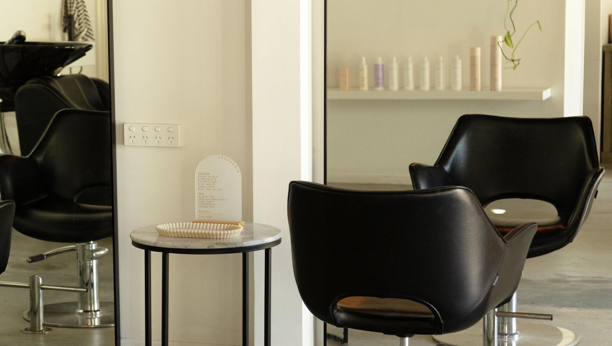 Sleek black salon chairs and a table at Lávue Hair, Wavell Heights, Queensland, AU, showcasing modern style.