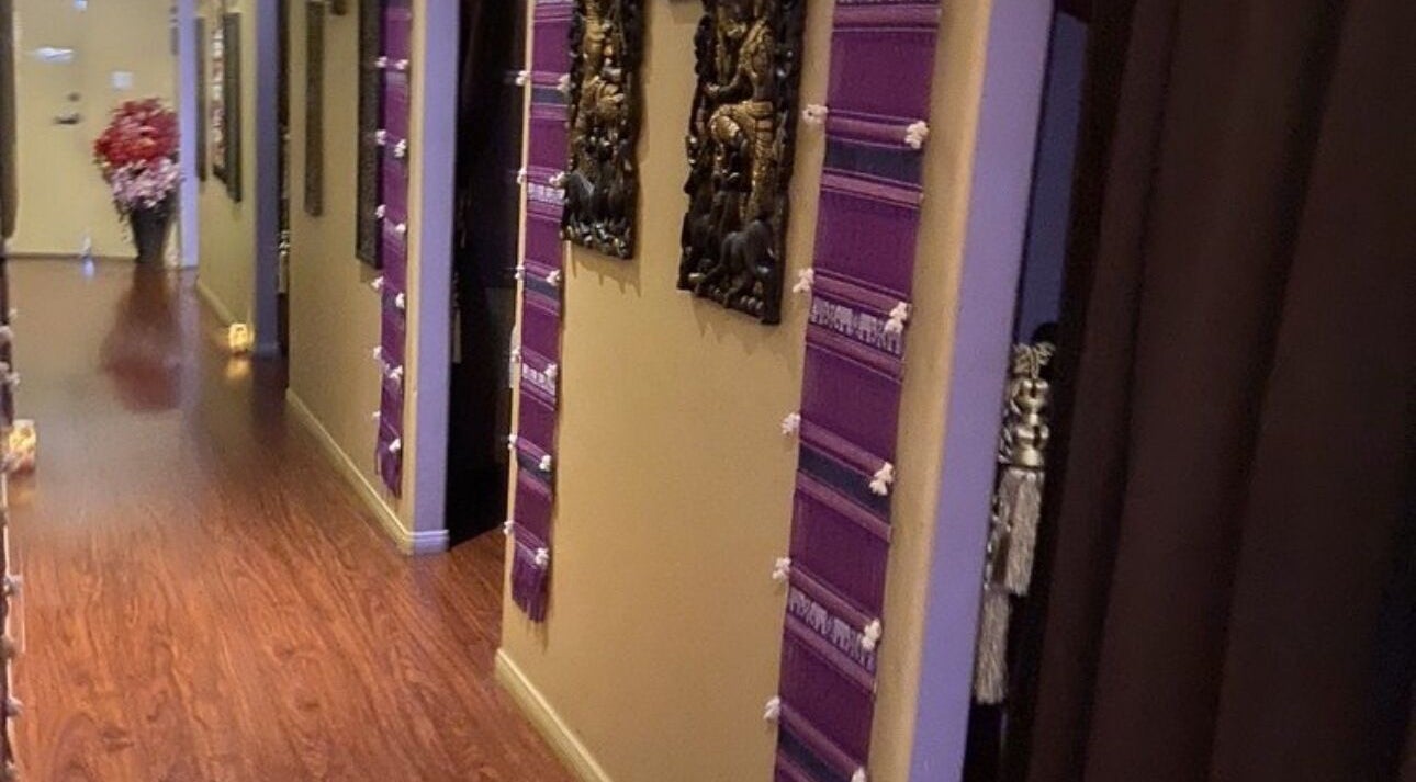 Elegant hallway at Royal Thai Massage in Santa Barbara, California, US, featuring wooden floors and traditional decor.