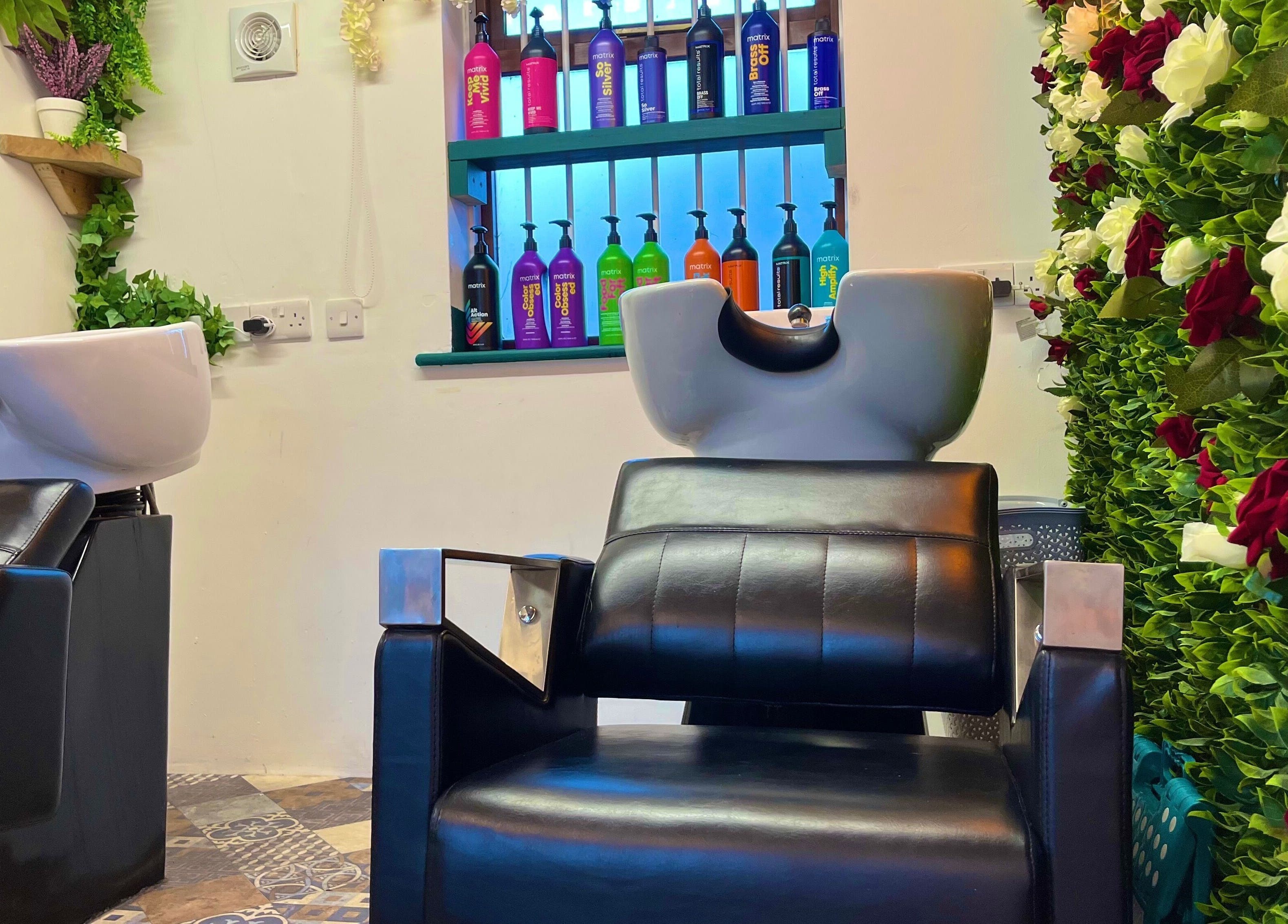 Modern salon chair at Redlocks Hair, Bournemouth, England, GB, with vibrant floral decor and product display.