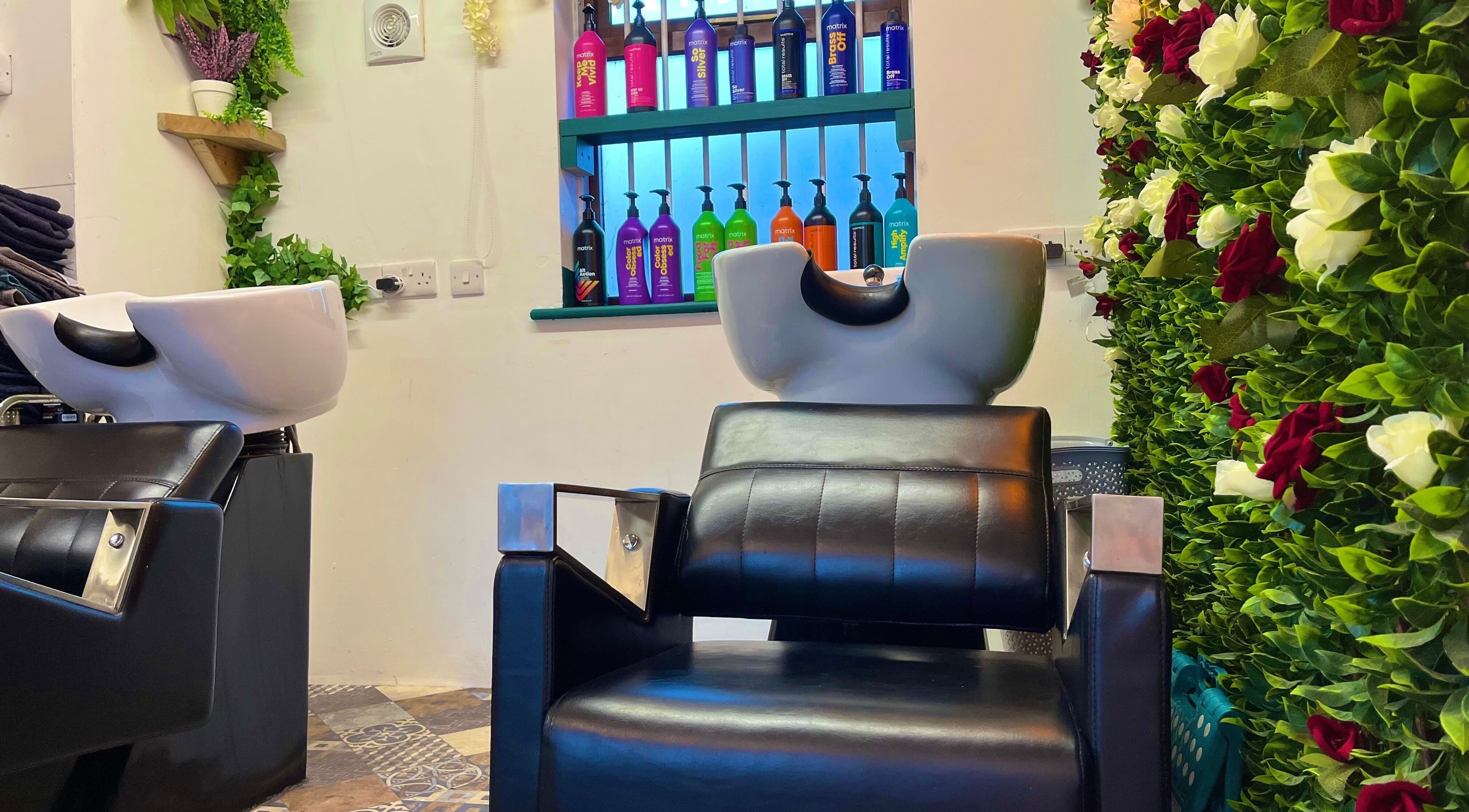 Modern salon chair at Redlocks Hair, Bournemouth, England, GB, with vibrant floral decor and product display.
