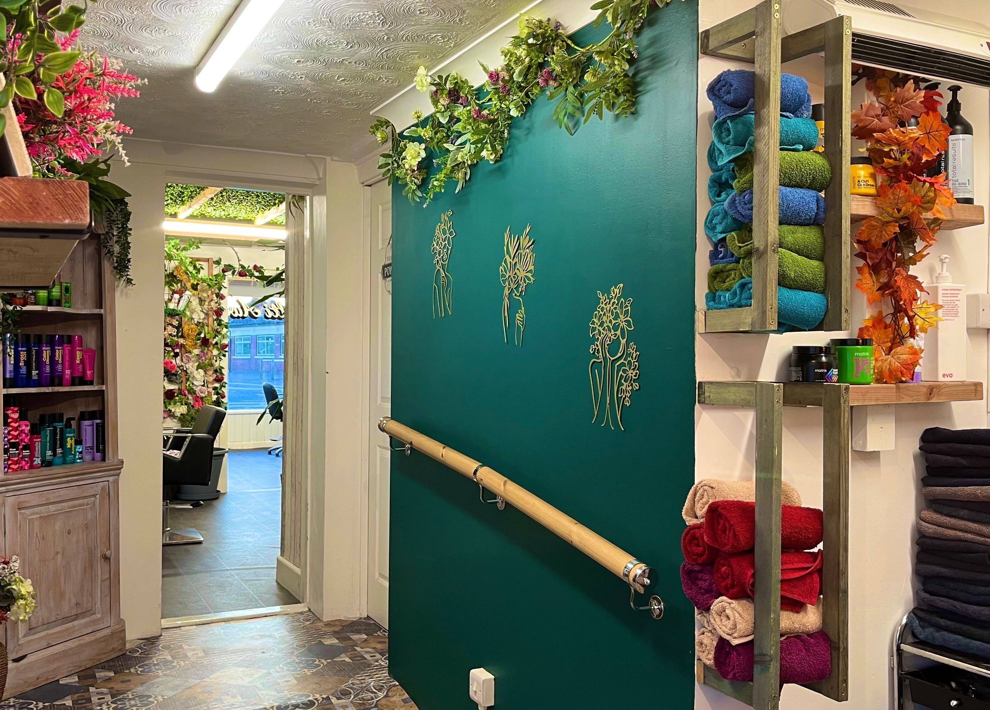 Decorative corridor at Redlocks Hair, Bournemouth, England, GB, with colorful towels and lush greenery.