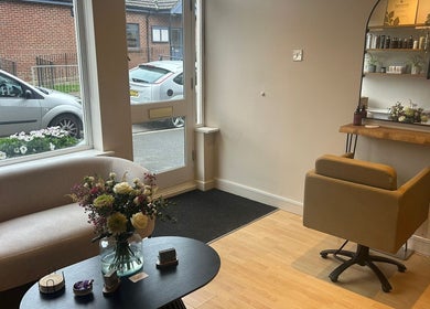 Cozy seating area at The Salon At Twenty Four, Woodford Halse, England, GB, with fresh flowers and a styling chair.