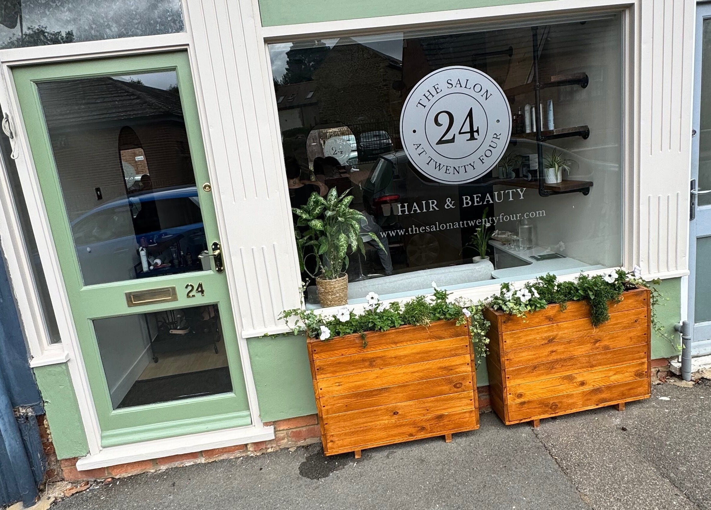 Front view of The Salon At Twenty Four in Woodford Halse, England, with stylish green door and planters.