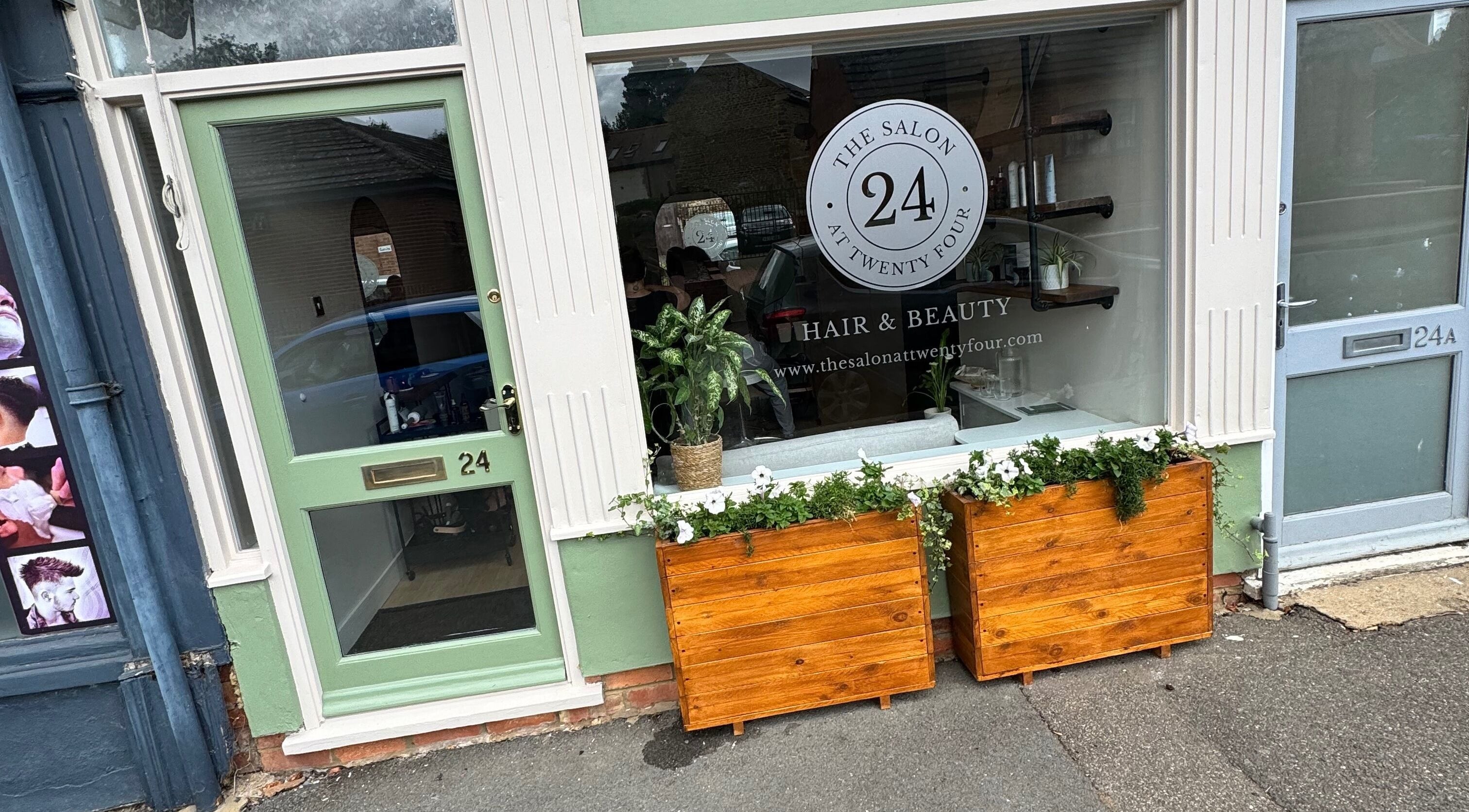 Front view of The Salon At Twenty Four in Woodford Halse, England, with stylish green door and planters.