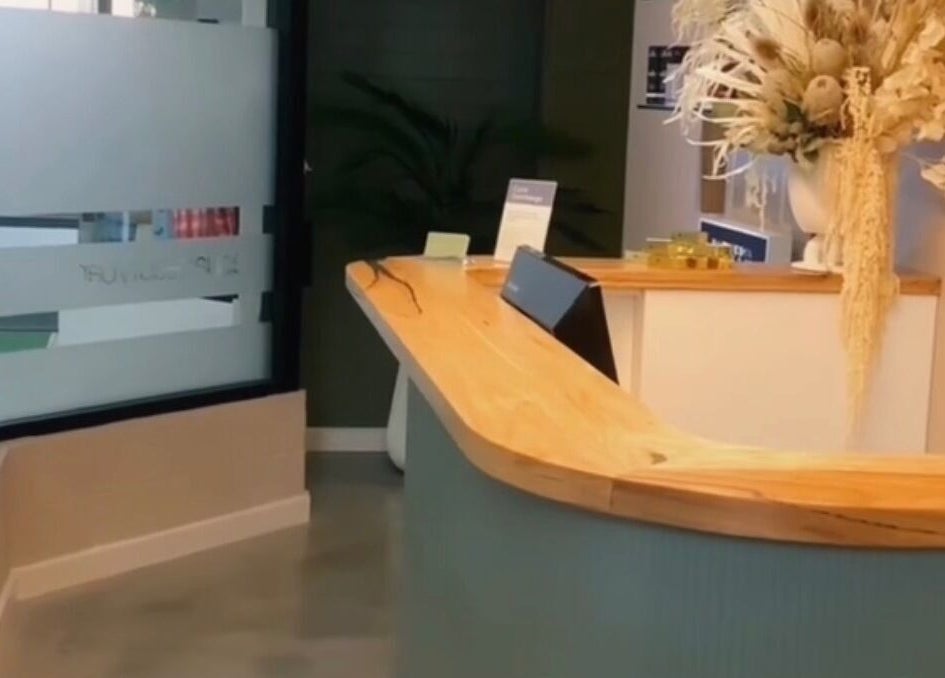 Chic reception at Aqua Beauty Bar, Melbourne, Victoria, AU, featuring stylish wood desk and floral decor.