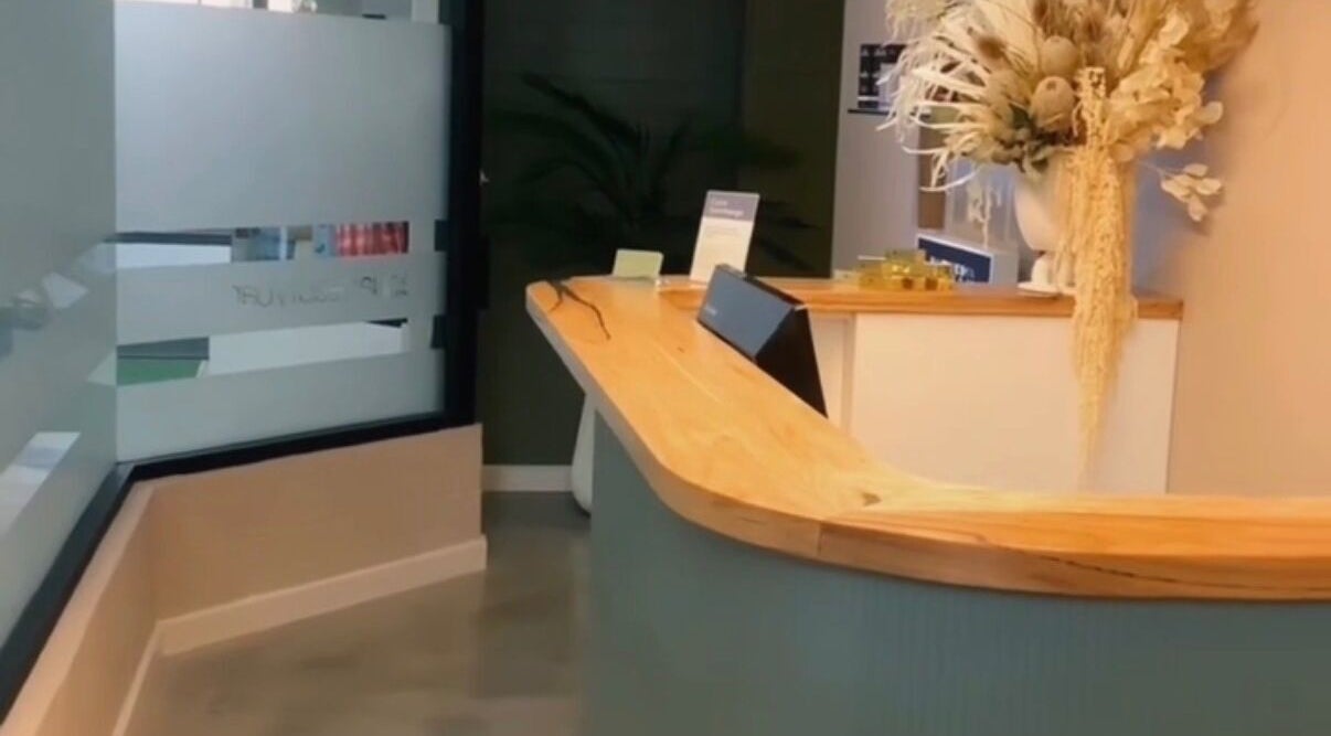 Chic reception at Aqua Beauty Bar, Melbourne, Victoria, AU, featuring stylish wood desk and floral decor.