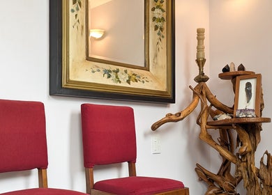 Elegant decor with red chairs and rustic wood art at Vanity Fair Beauty & Skin Care Salon, Auckland, NZ.