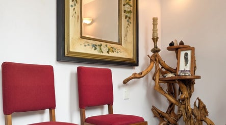 Elegant decor with red chairs and rustic wood art at Vanity Fair Beauty & Skin Care Salon, Auckland, NZ.