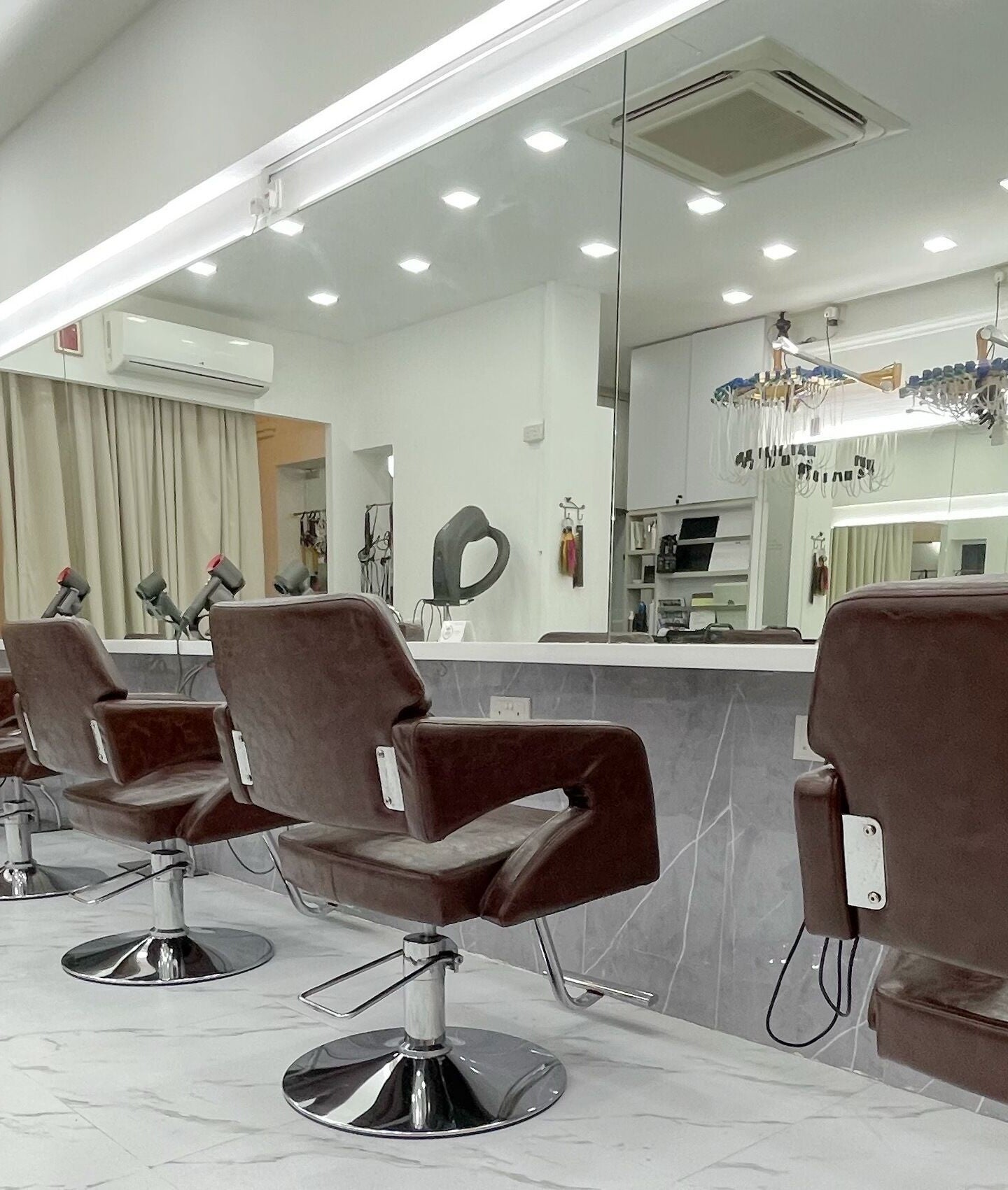 Modern interior of HAVA Hair with chic brown salon chairs in Complex, SG, reflecting luxury and style.