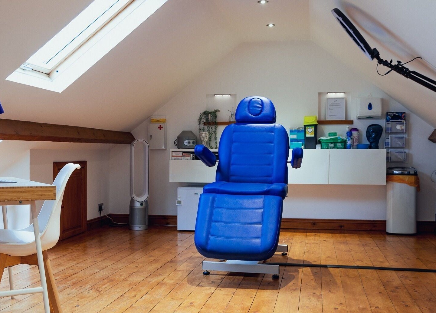 Modern treatment room at Gower Skin Aesthetics, Kittle, Wales, GB with blue reclining chair and skylight.