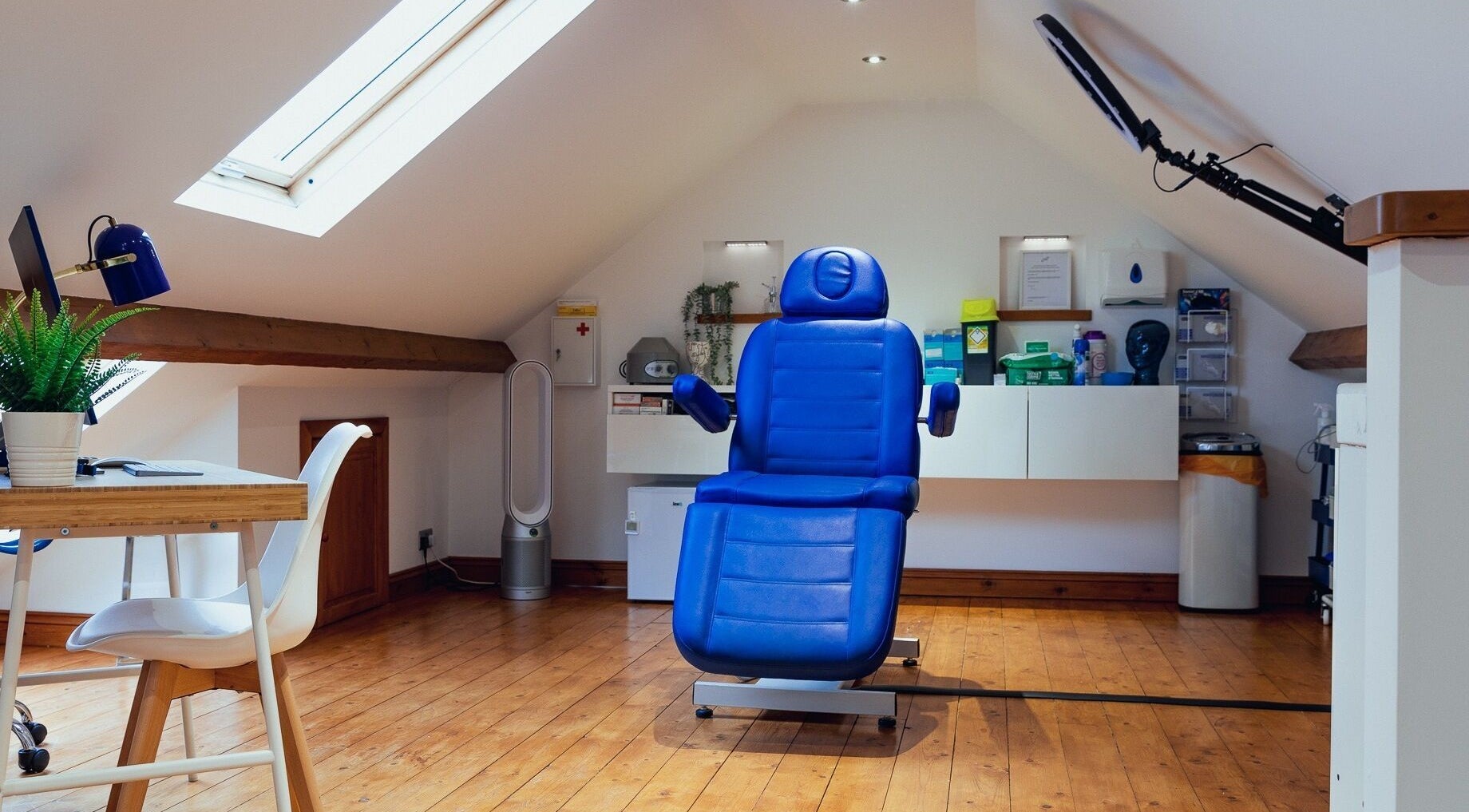 Modern treatment room at Gower Skin Aesthetics, Kittle, Wales, GB with blue reclining chair and skylight.