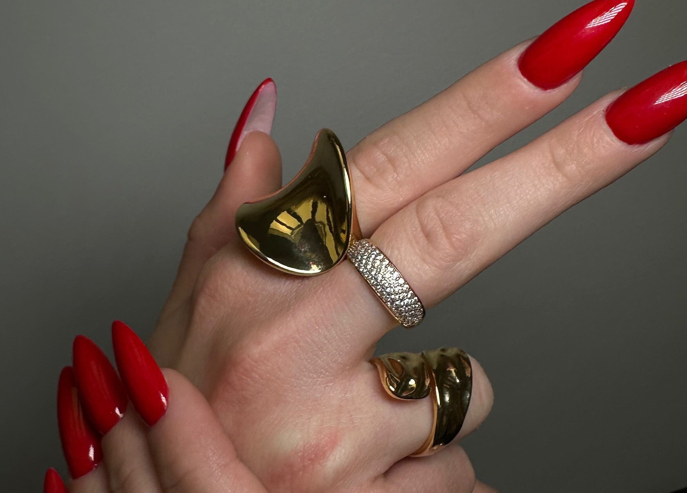 Elegant red manicured nails with gold rings at SBI SALON, Englishtown, New Jersey, US.