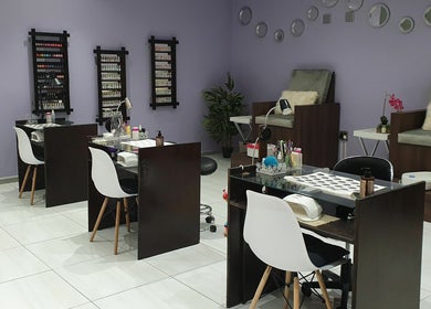 Chic interior of Beaunique Beauty Studio Casino in Welkom, Free State, ZA, featuring nail stations and comfy chairs.