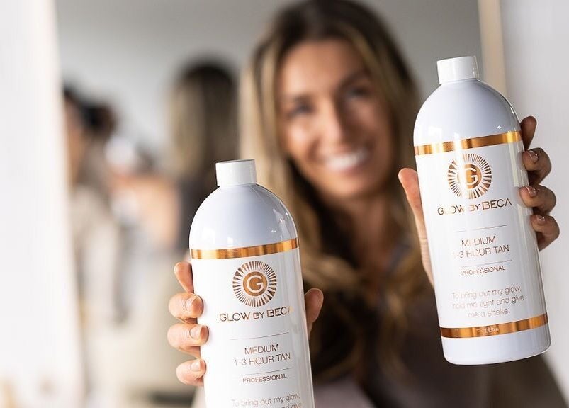 Smiling woman showcasing GlowbyBeca tanning products at Wilton, New South Wales, AU salon.