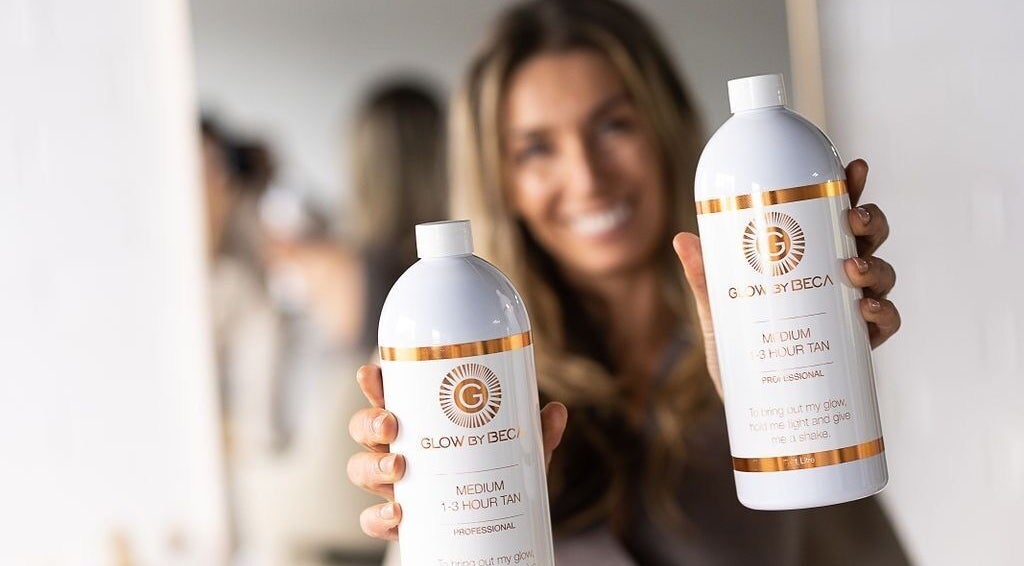 Smiling woman showcasing GlowbyBeca tanning products at Wilton, New South Wales, AU salon.