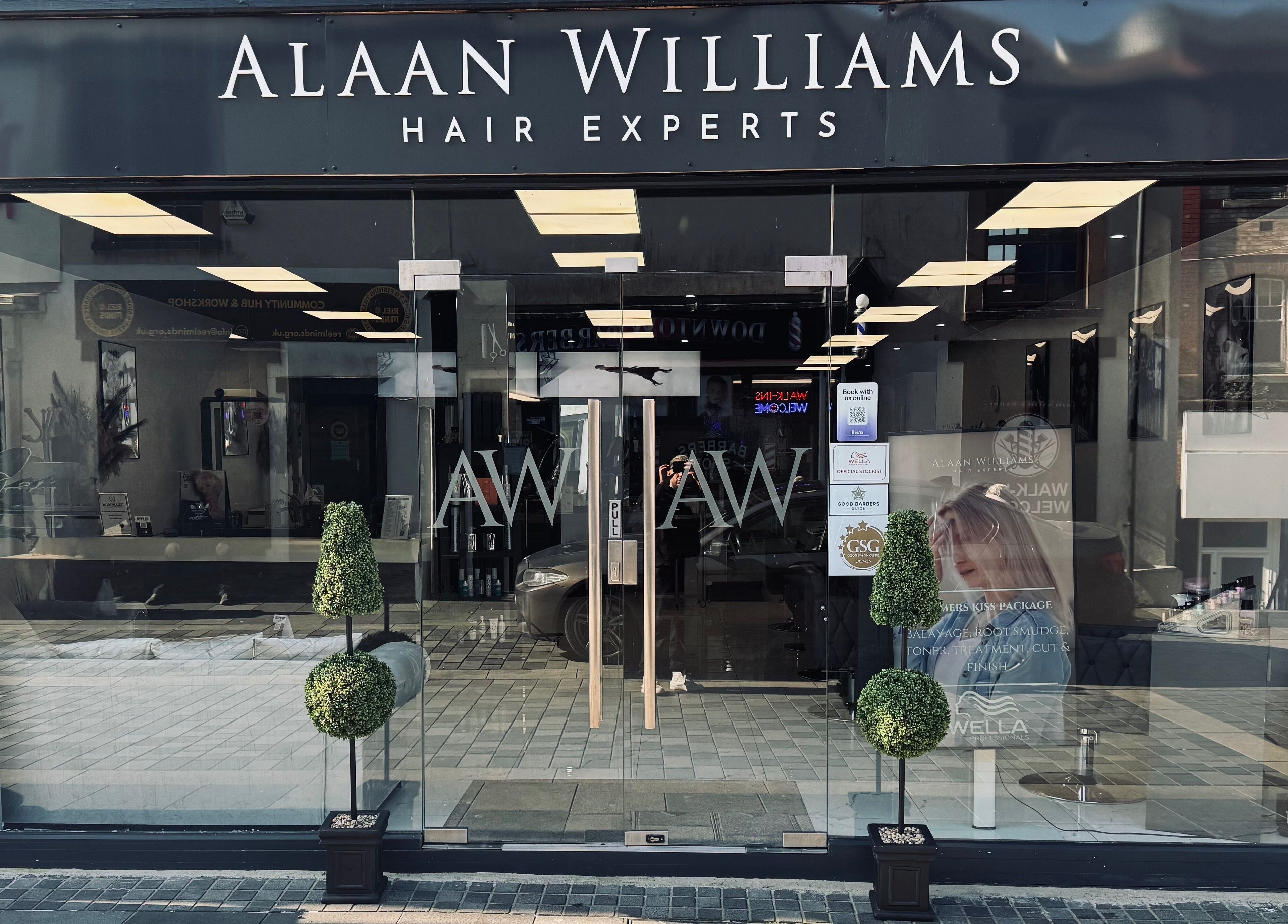 Front view of Alaan Williams Hair Experts in Pontypridd, Wales, GB with stylish signage and greenery.