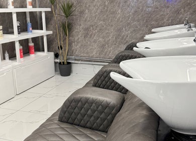 Modern wash basins at Alaan Williams Hair Experts in Pontypridd, Wales, GB, alongside sleek shelving.