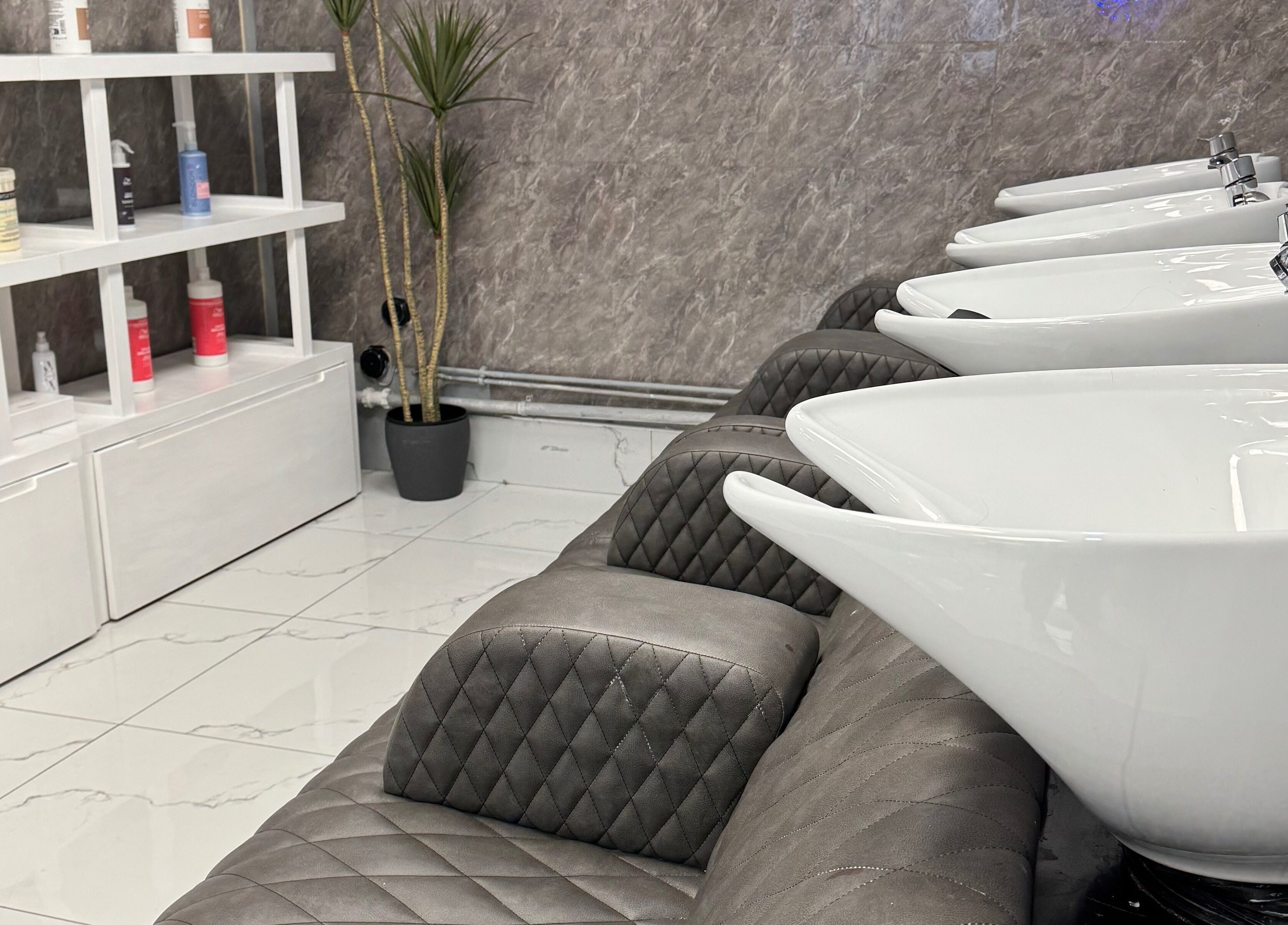 Modern wash basins at Alaan Williams Hair Experts in Pontypridd, Wales, GB, alongside sleek shelving.