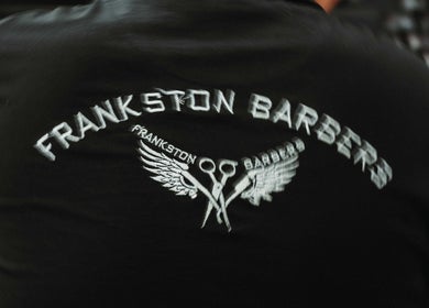 Frankston Barbers logo on black fabric, Melbourne, Victoria, AU, featuring scissors and wings.