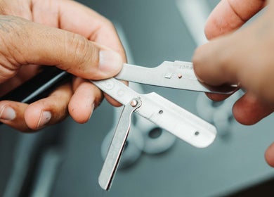 Close-up of a barber holding a razor at Frankston Barbers, Melbourne, Victoria, AU.