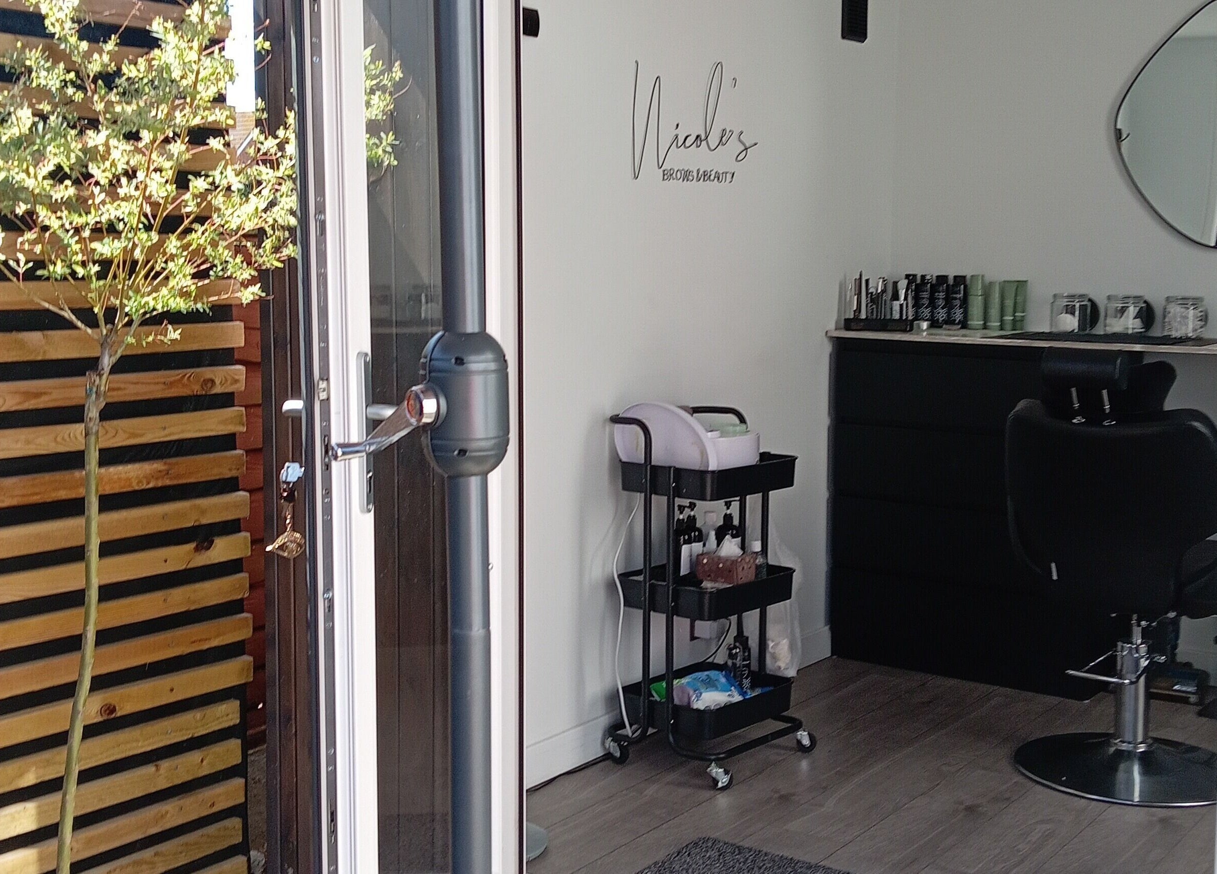 Entrance to Nicole's Brows and Beauty in Minster On Sea, England, showcasing chic interior with a styling chair.