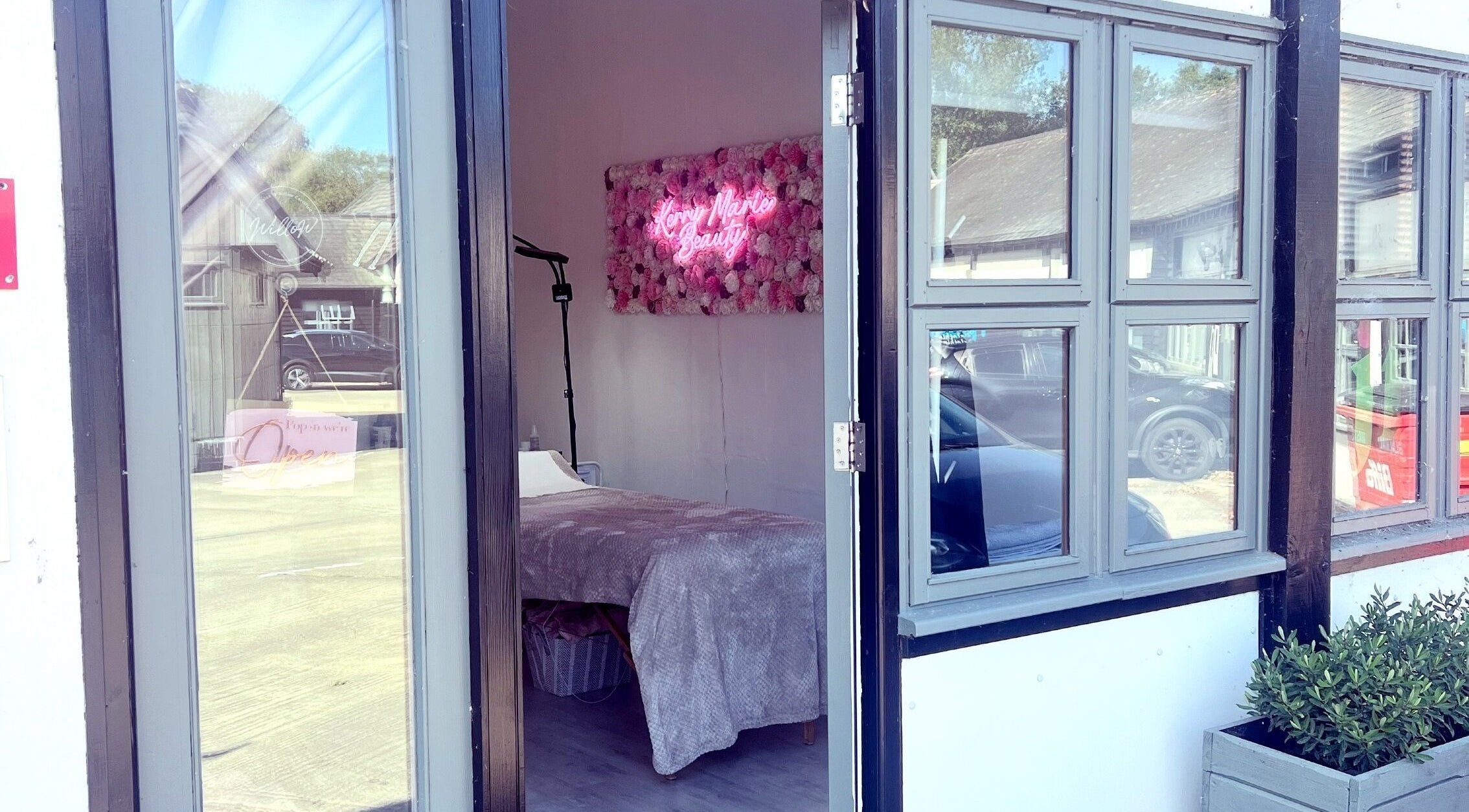 Entrance to Kerry Marie Beauty in Steeple Bumpstead, England, featuring a cozy interior with neon sign.