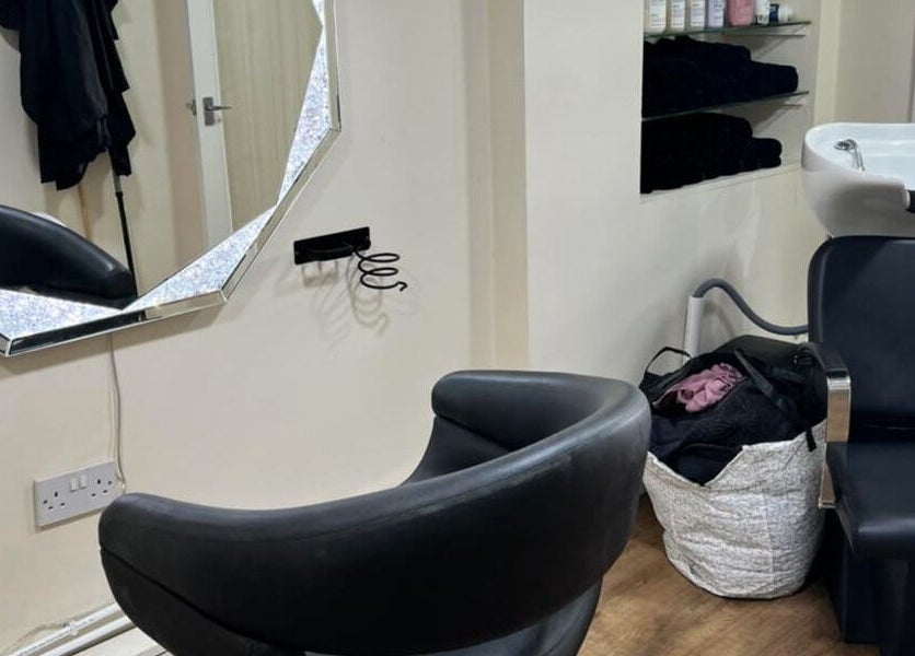Interior of David Charles Hair, Health and Beauty Studio in Raunds, England, GB showing a stylish salon chair and mirror.