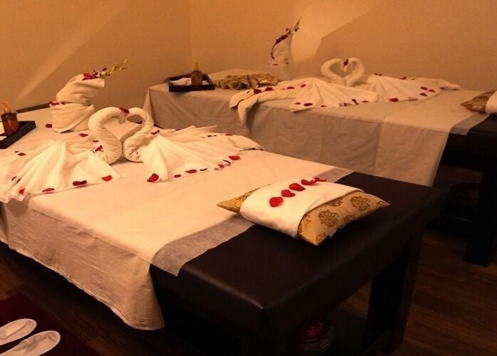 Elegant couple's massage setup at Body Raaga Wellness Spa - Jp Nagar, Bengaluru, Karnataka, IN, with towel art and petals.