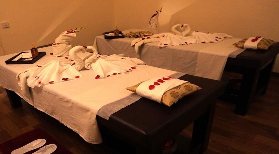 Elegant couple's massage setup at Body Raaga Wellness Spa - Jp Nagar, Bengaluru, Karnataka, IN, with towel art and petals.