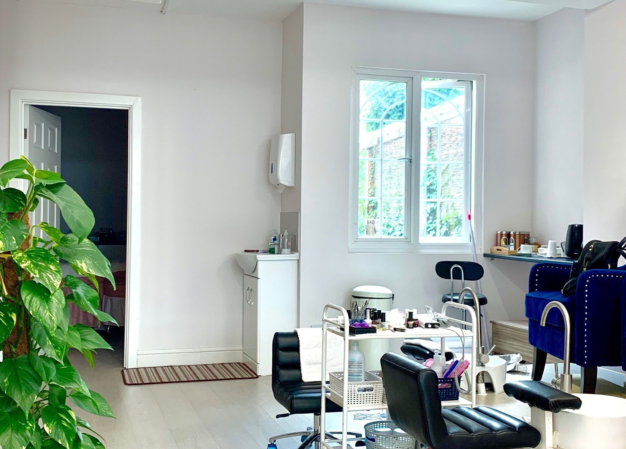 Modern beauty salon interior at Milly and Jin, Hove, England, GB, featuring stylish chairs and lush greenery.