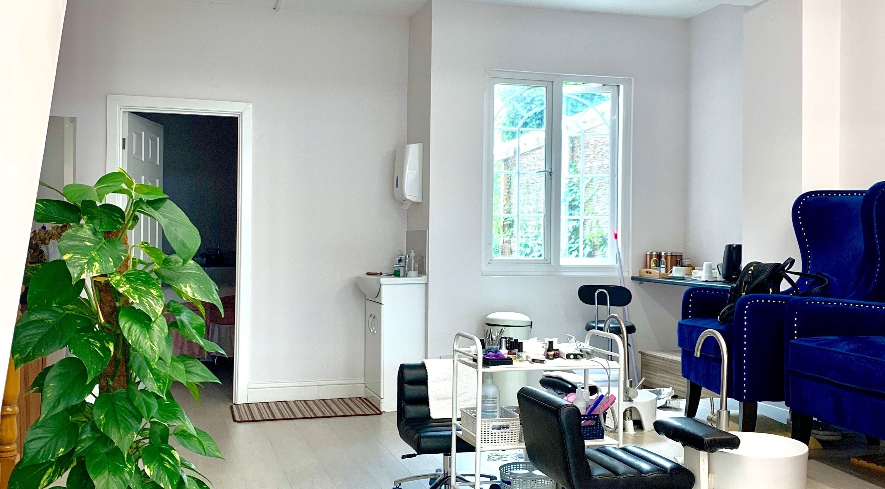 Modern beauty salon interior at Milly and Jin, Hove, England, GB, featuring stylish chairs and lush greenery.