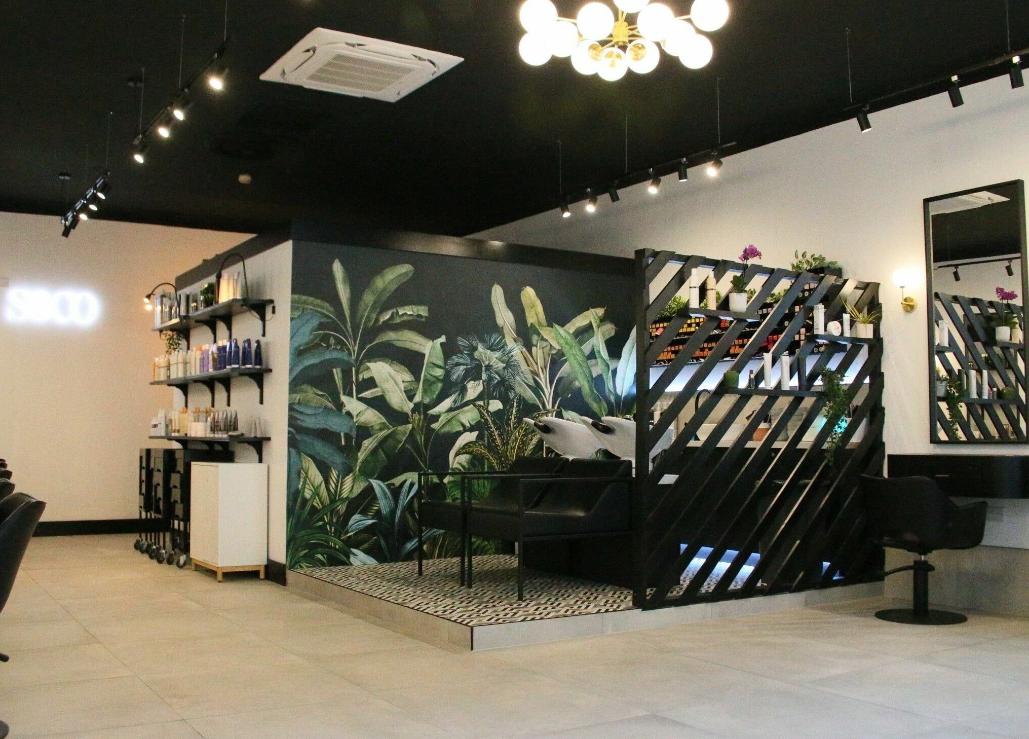 Elegant salon interior at Simpson and Co, Stirling, Scotland, GB, featuring modern black chairs and lush decor.