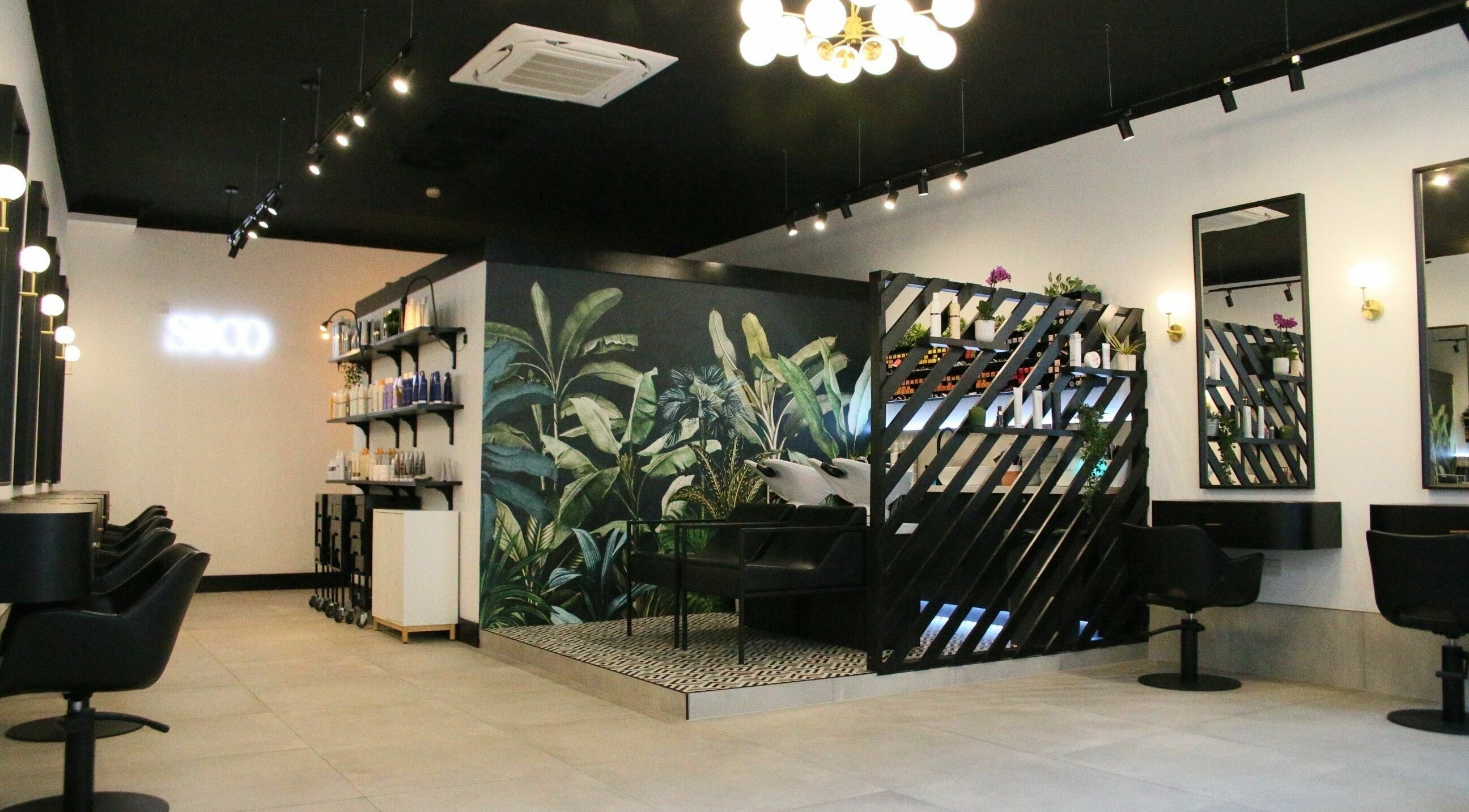 Elegant salon interior at Simpson and Co, Stirling, Scotland, GB, featuring modern black chairs and lush decor.