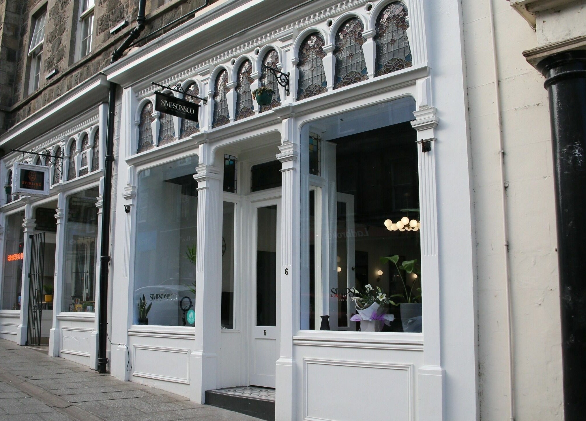 Entrance of Simpson and Co in Stirling, Scotland, GB with elegant white exterior and large windows.