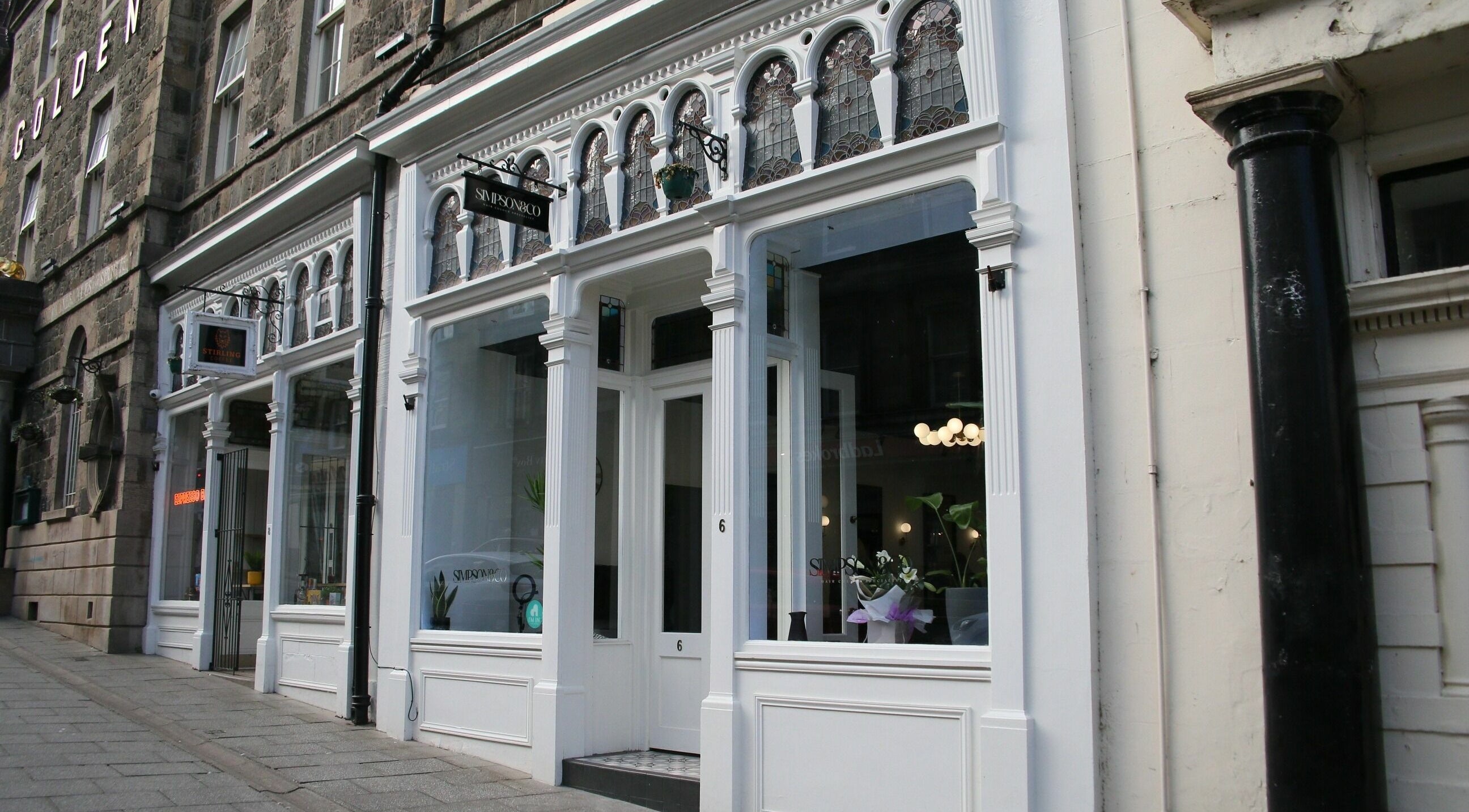 Entrance of Simpson and Co in Stirling, Scotland, GB with elegant white exterior and large windows.