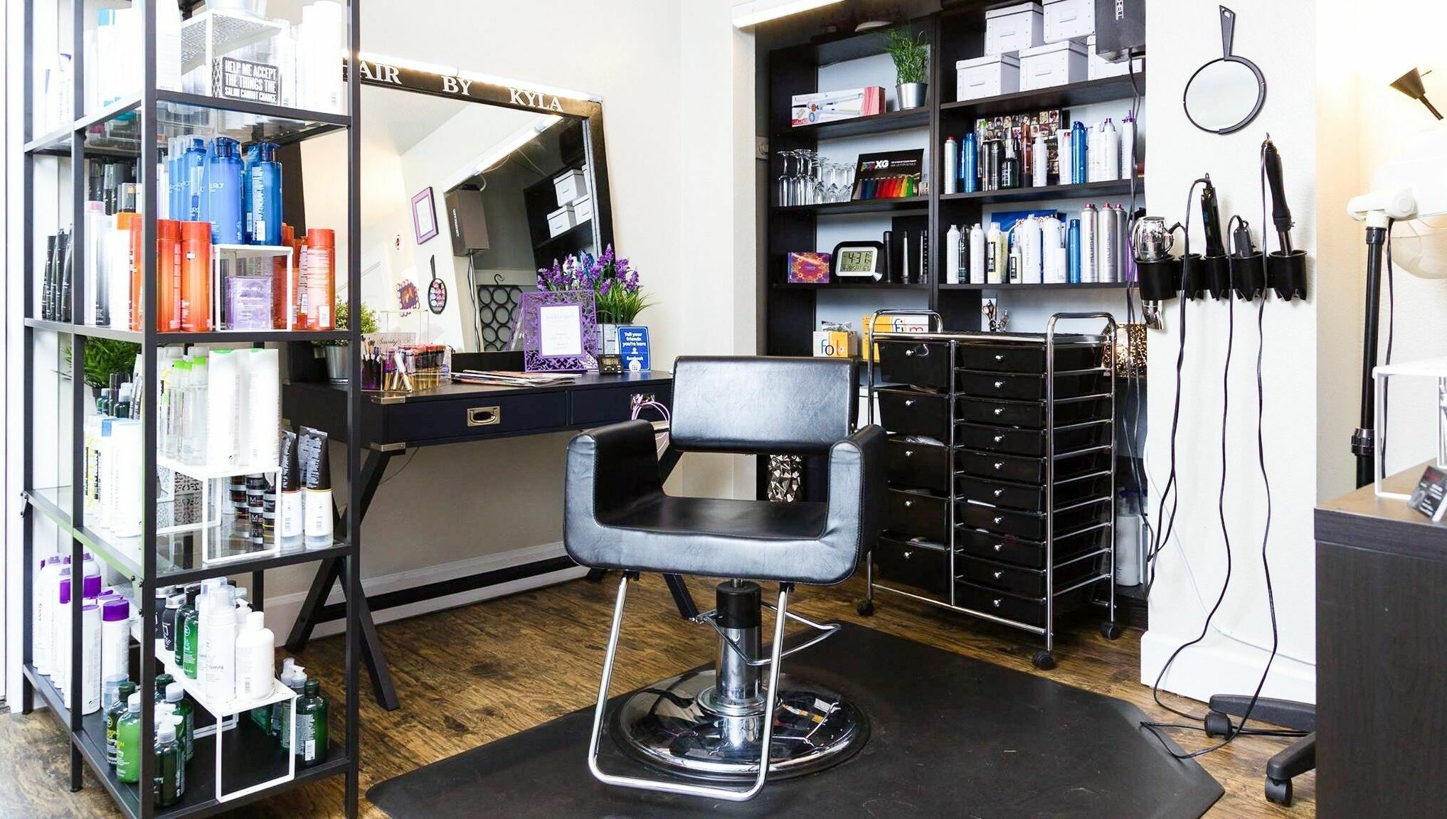 Stylish salon interior at Hair By Kyla, Vancouver, Washington, US, featuring a sleek chair and product shelves.
