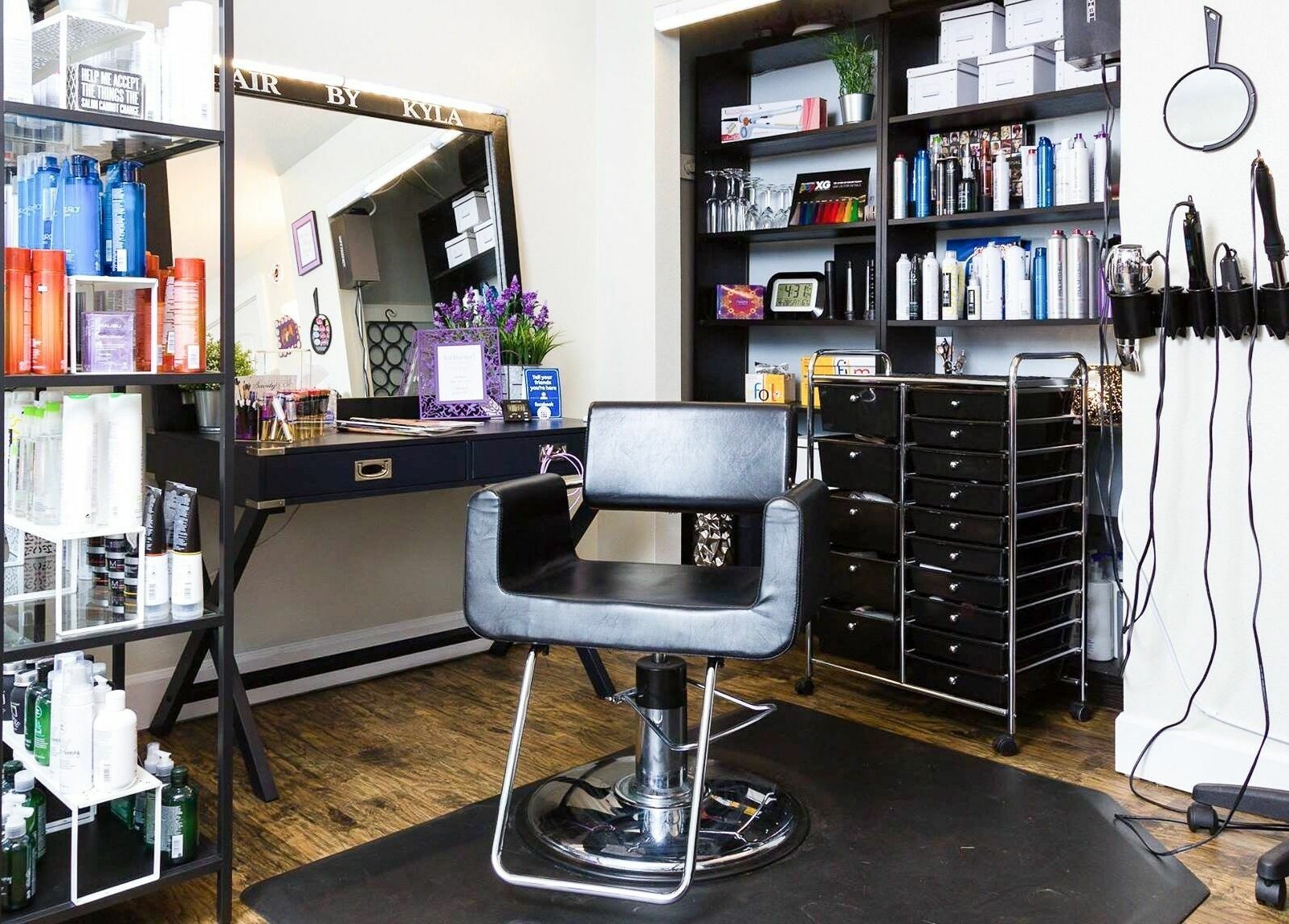 Stylish salon interior at Hair By Kyla, Vancouver, Washington, US, featuring a sleek chair and product shelves.