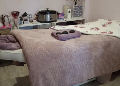 Cozy massage table at Kalmin’ Therapies, Rushden, England, GB, adorned with soft linens and hot stones.
