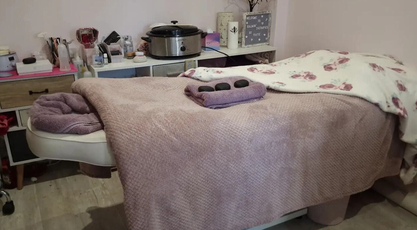 Cozy massage table at Kalmin’ Therapies, Rushden, England, GB, adorned with soft linens and hot stones.