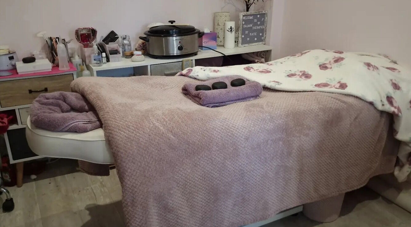Cozy massage table at Kalmin’ Therapies, Rushden, England, GB, adorned with soft linens and hot stones.