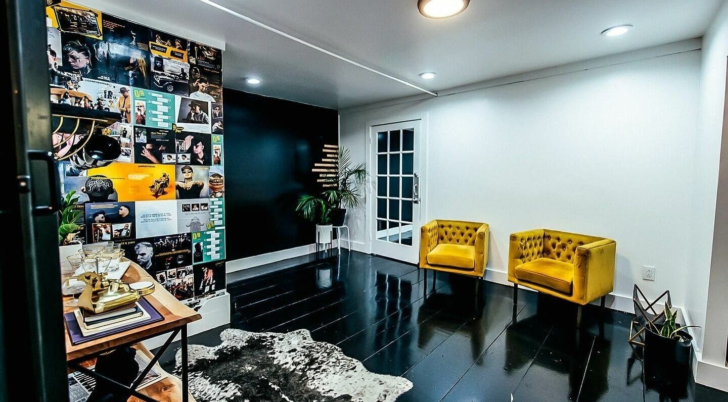 Stylish interior of B | K L A S S Y Barber Studio in Kansas City with yellow chairs and collage wall.