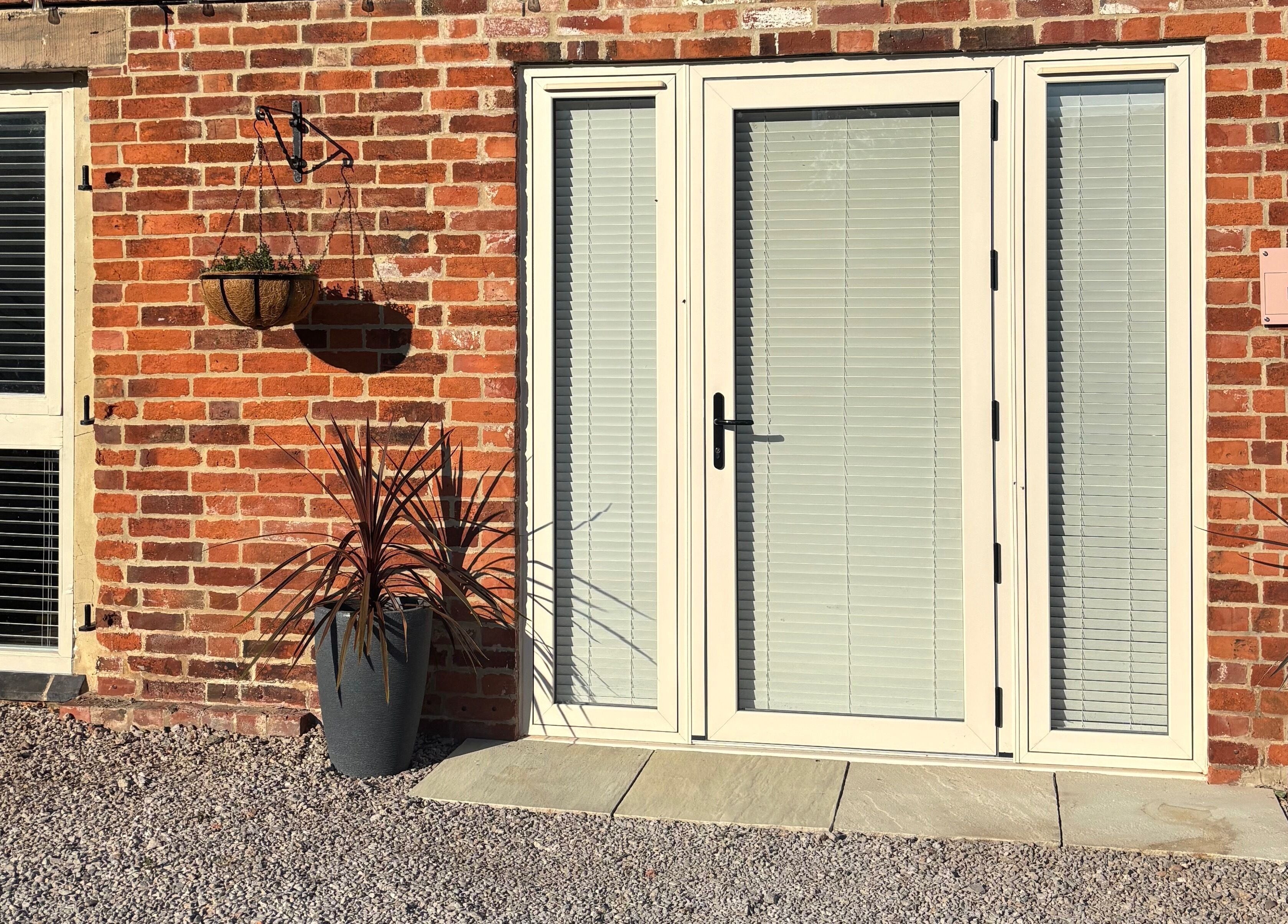 Charming brick entryway of Beauty at The CowShed in Uttoxeter, England, GB, featuring potted plants and hanging basket.