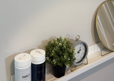 Elegant shelf with decor at Mark One Beauty, Exeter, England, GB, featuring a clock, mirror, and plant.
