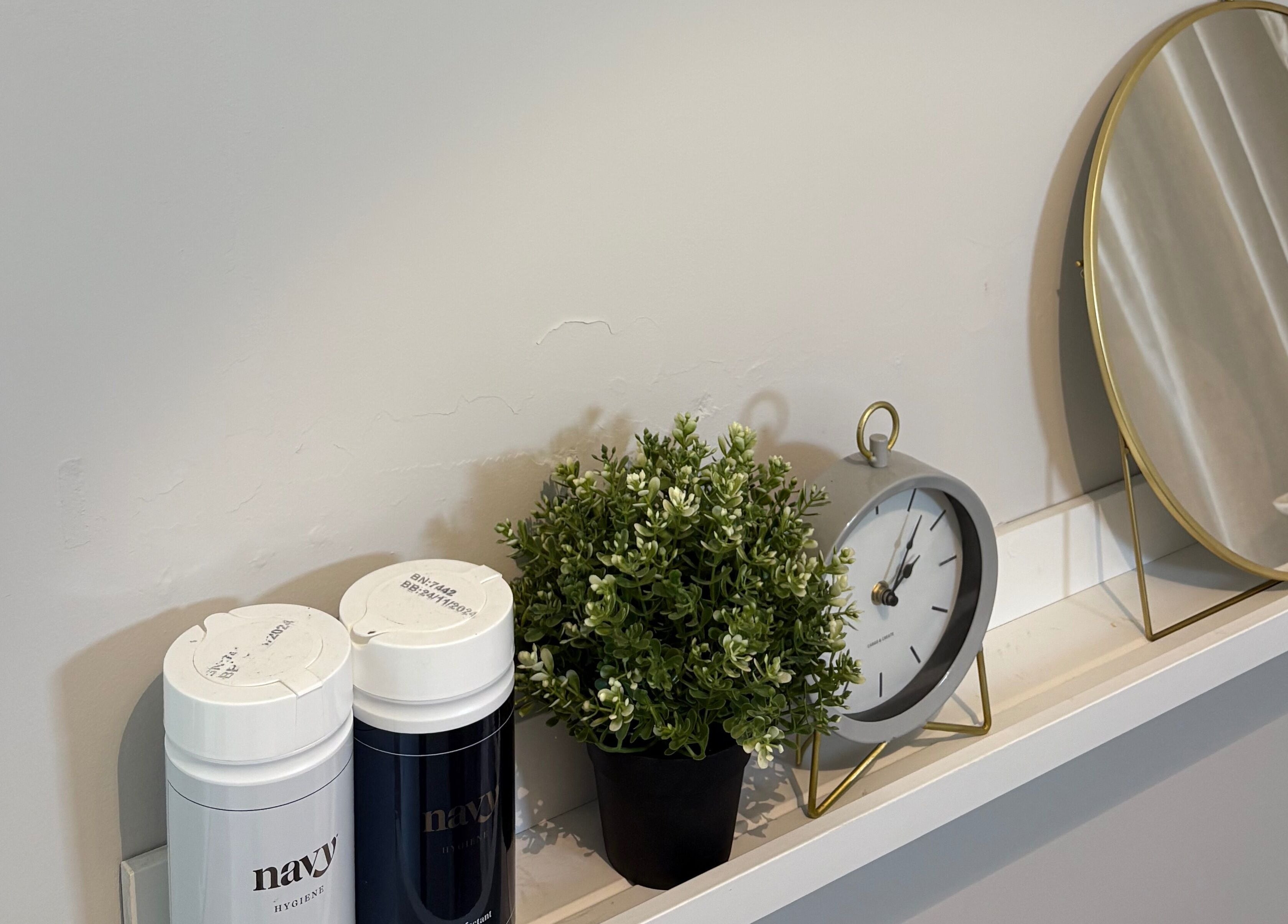 Elegant shelf with decor at Mark One Beauty, Exeter, England, GB, featuring a clock, mirror, and plant.