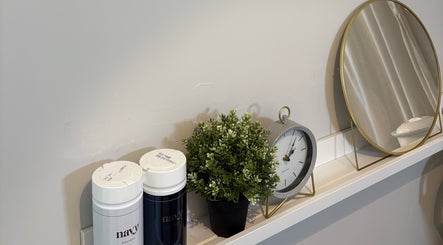 Elegant shelf with decor at Mark One Beauty, Exeter, England, GB, featuring a clock, mirror, and plant.
