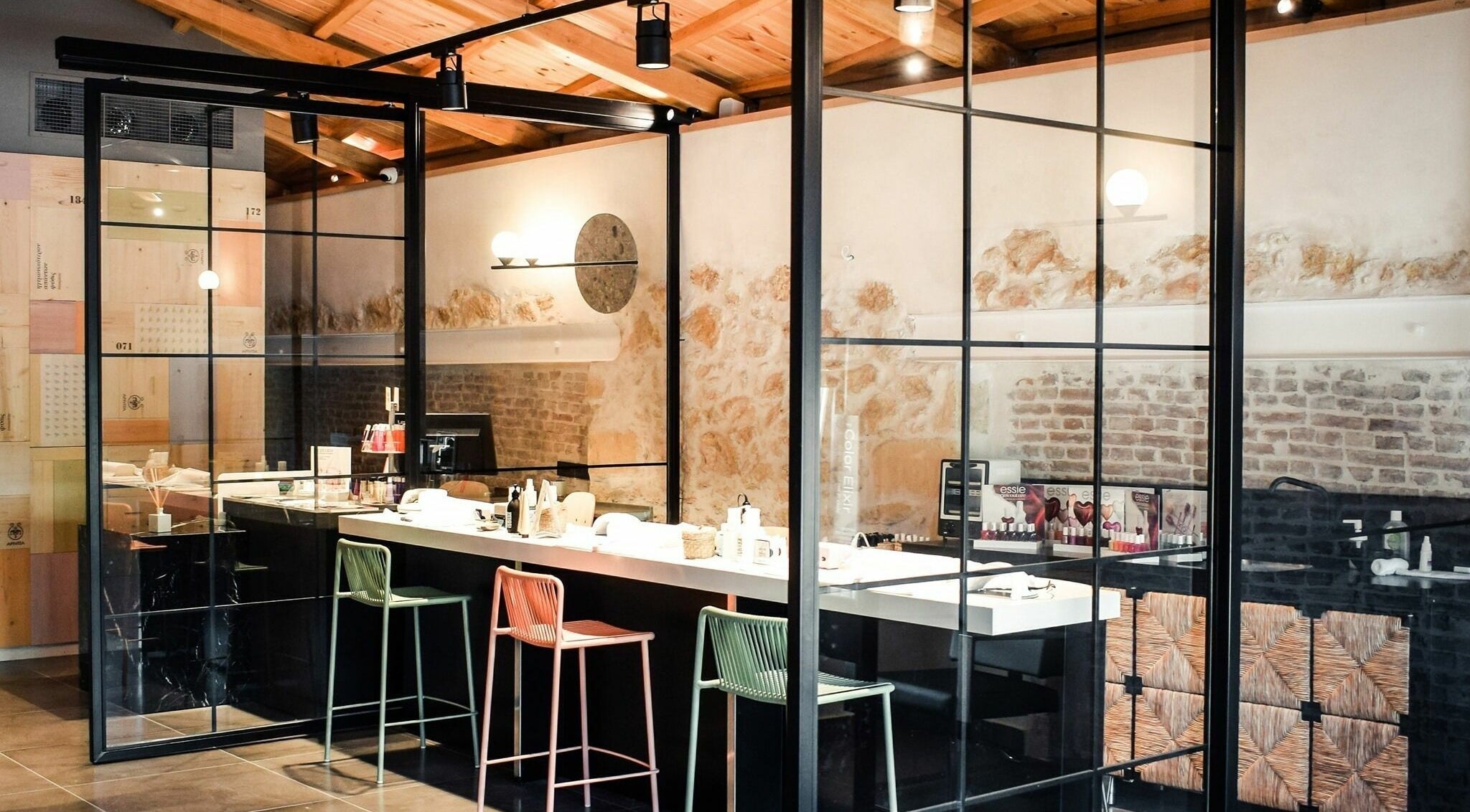 Σύγχρονος εσωτερικός χώρος του Apotheke Spa, Χανιά, GR με μαύρους πάγκους και καρέκλες μπαρ.