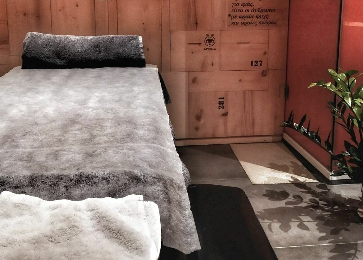 Χαλαρωτικός χώρος μασάζ στο Apotheke Spa, Χανιά, GR με πράσινο φυτό και απαλό φωτισμό.